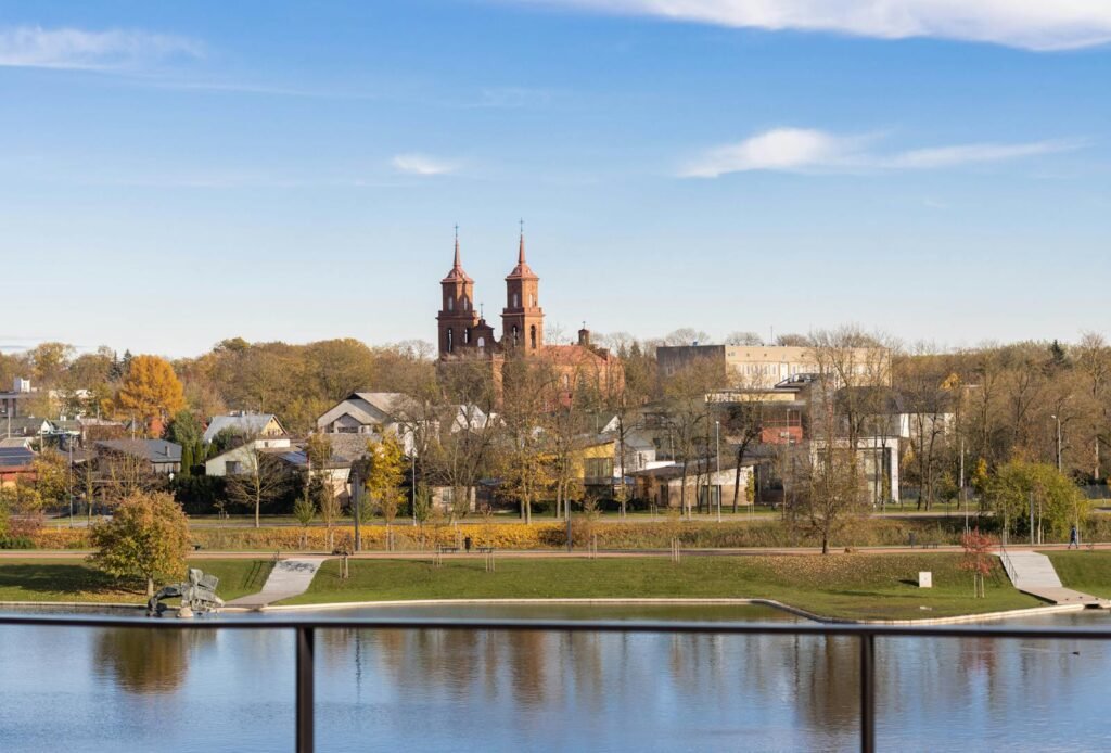 A picturesque aerial view of Panevėžys, Lithuania featuring a historic church and autumn foliage.