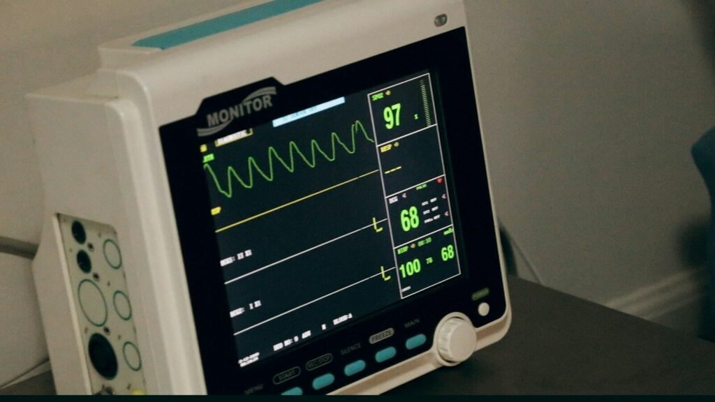 A medical monitor displaying vital signs with green waveforms on a dark screen