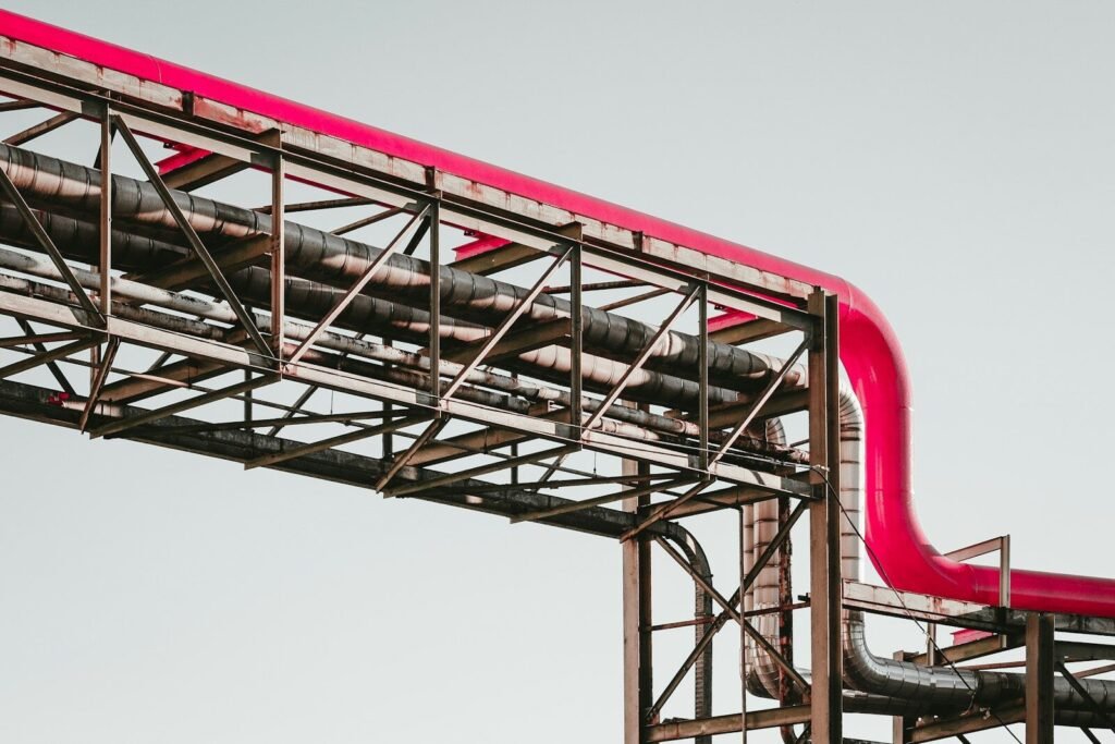 A bright pink industrial pipe running along a metal support structure